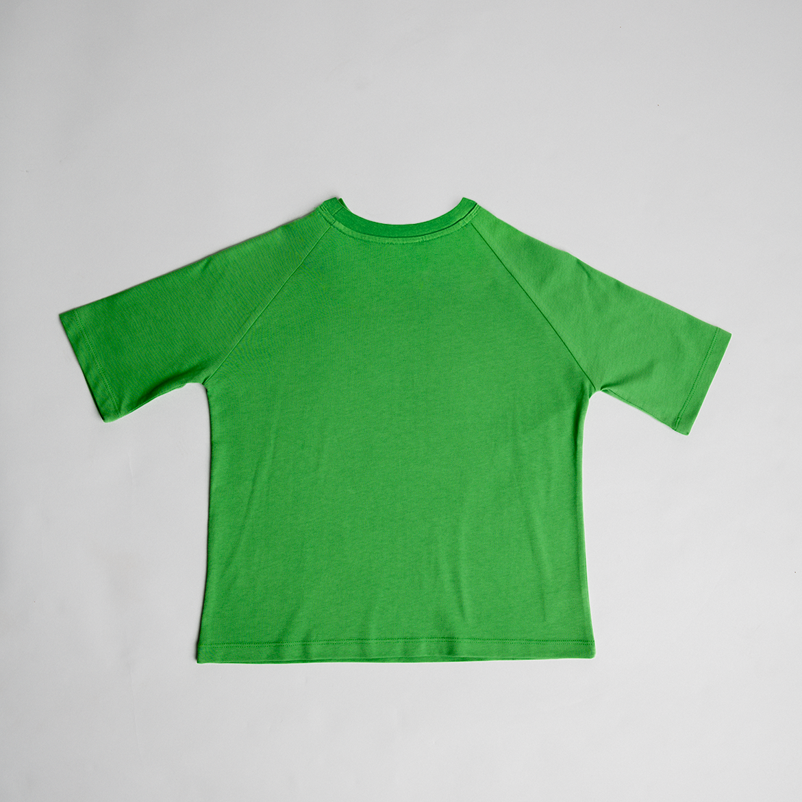 Green oversized cotton tee laid flat, showcasing relaxed fit and soft fabric for the Grow - Oversized Tee.