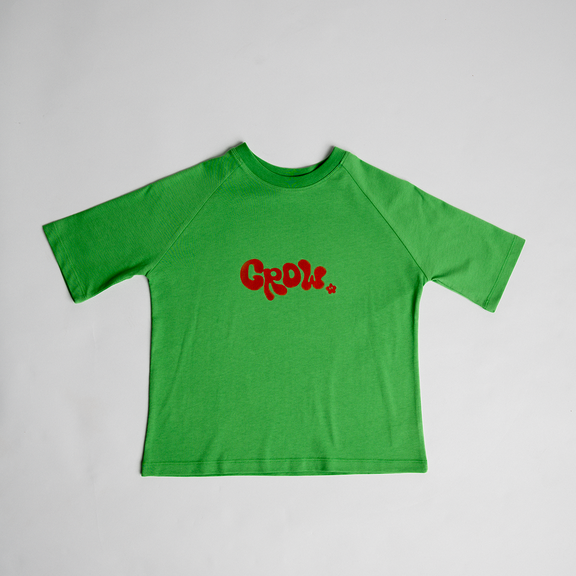 Green oversized cotton tee with bold red "Grow" lettering, designed for comfort and unisex wear, Grow - Oversized Tee.