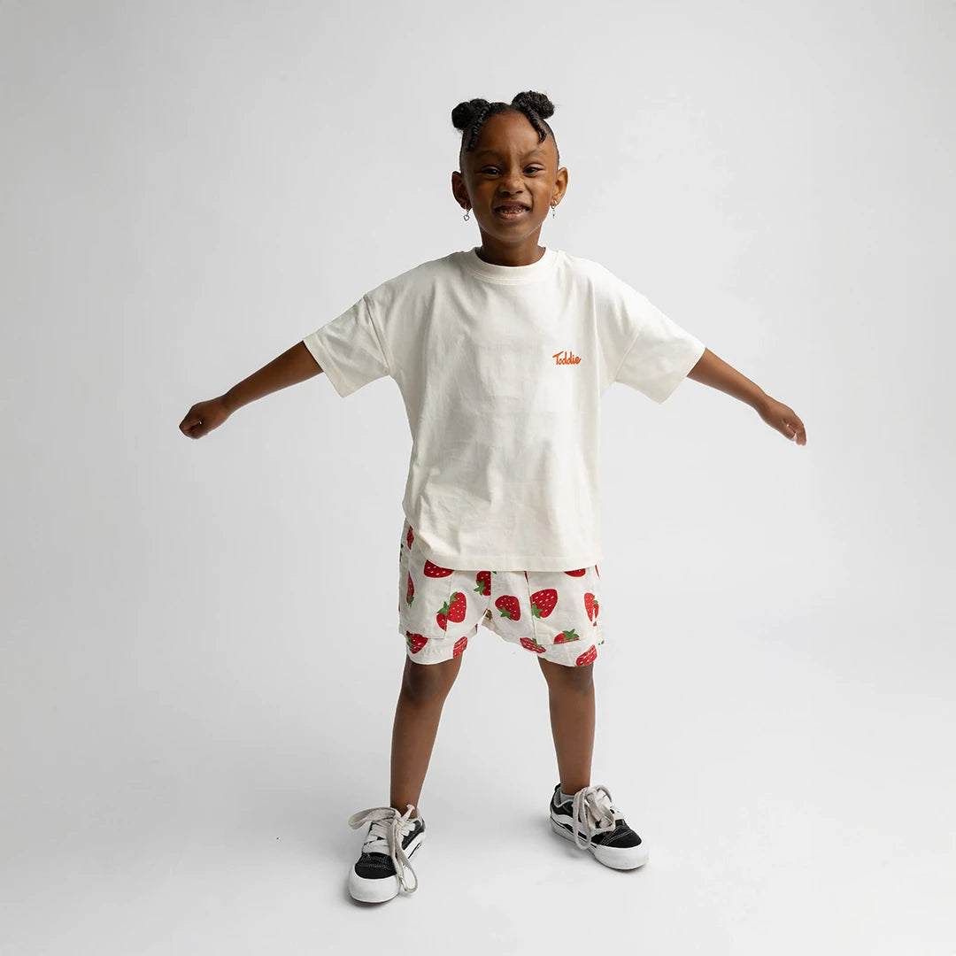 Child wearing Juicy Tomato - Oversized Tee with relaxed fit and tomato graphic shorts in a bright studio setting.