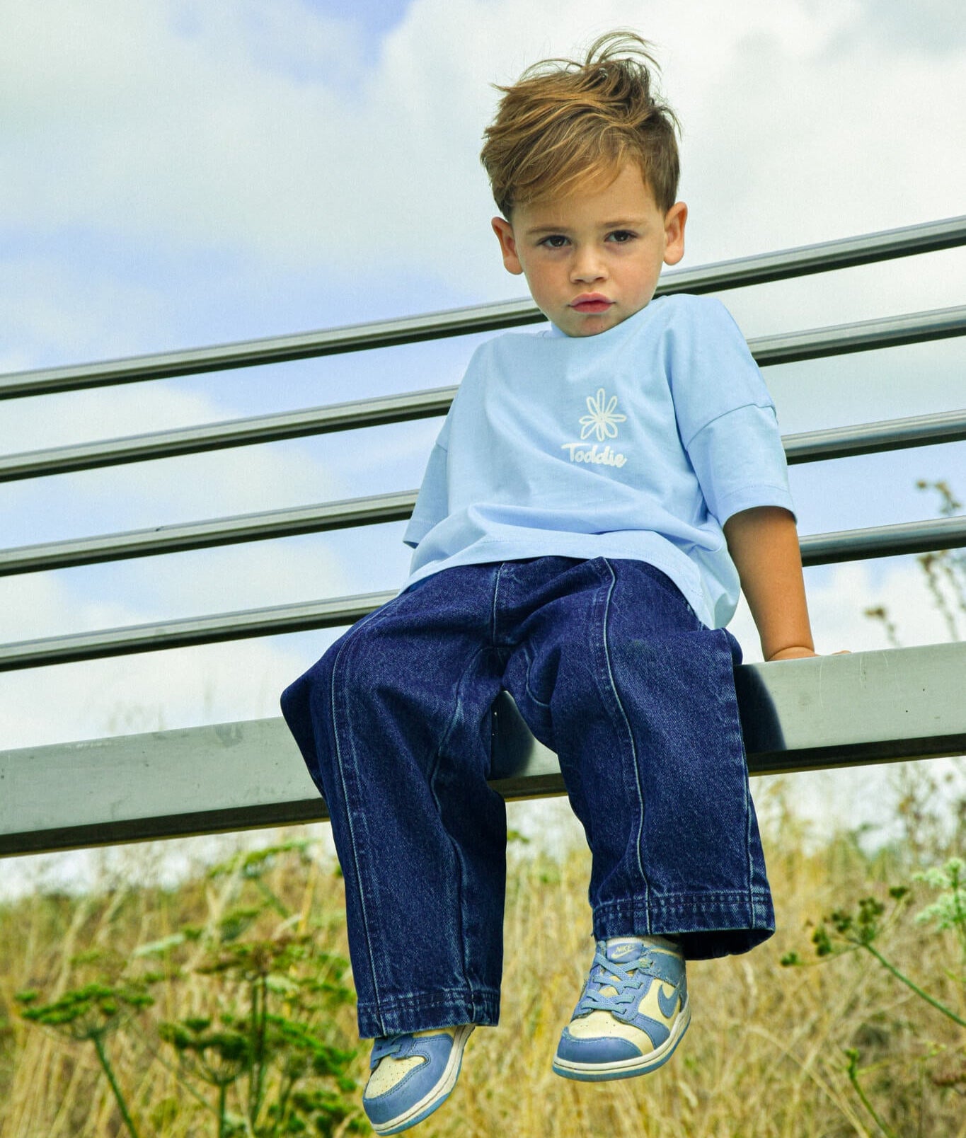 Young boy sitting outdoors wearing Balloon styled - Denim Jeans with a soft elastic waistband and Toddie logo embroidery.
