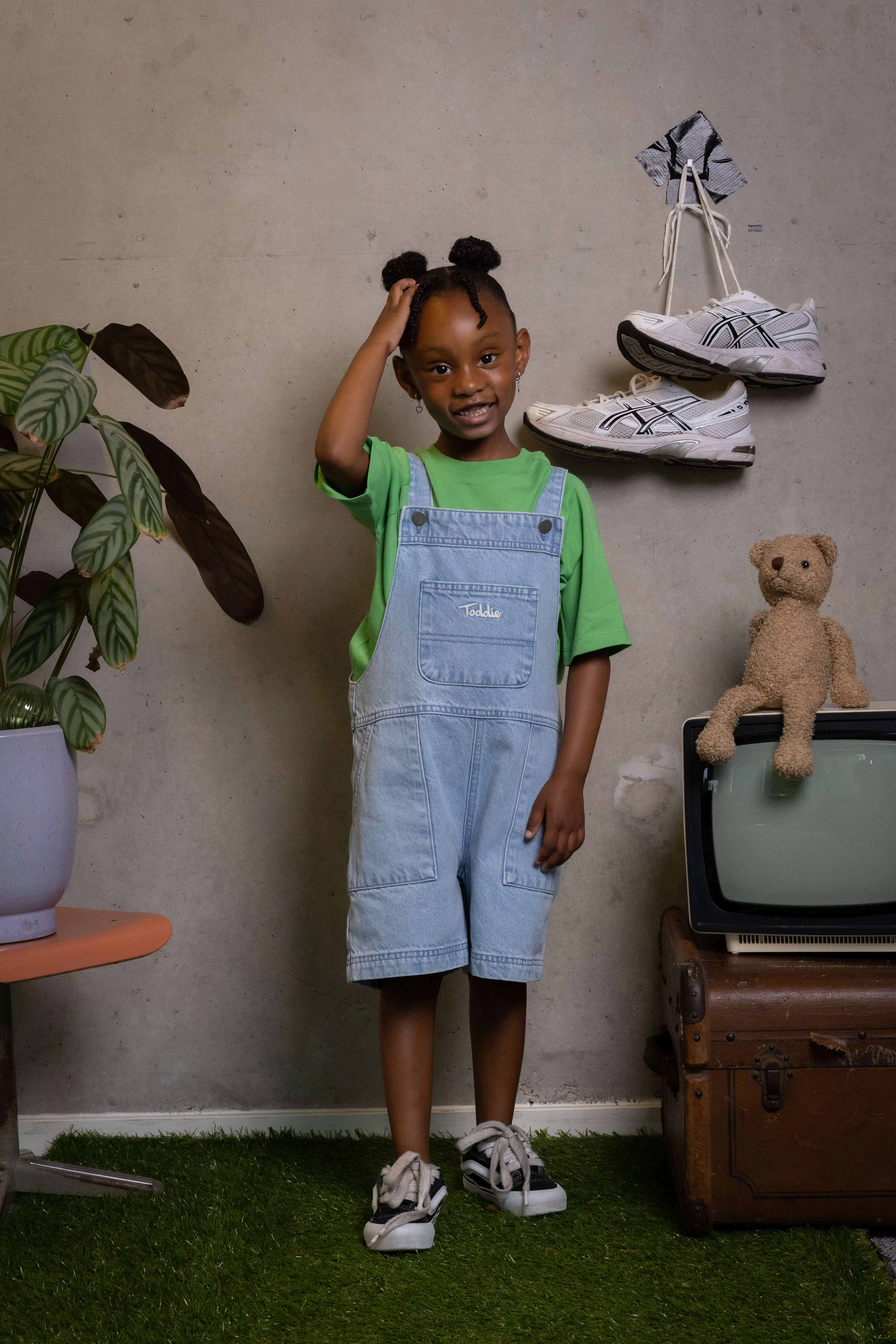 Confident kid rocking FIT #12 denim overalls with real style and a smile, only from Toddie.