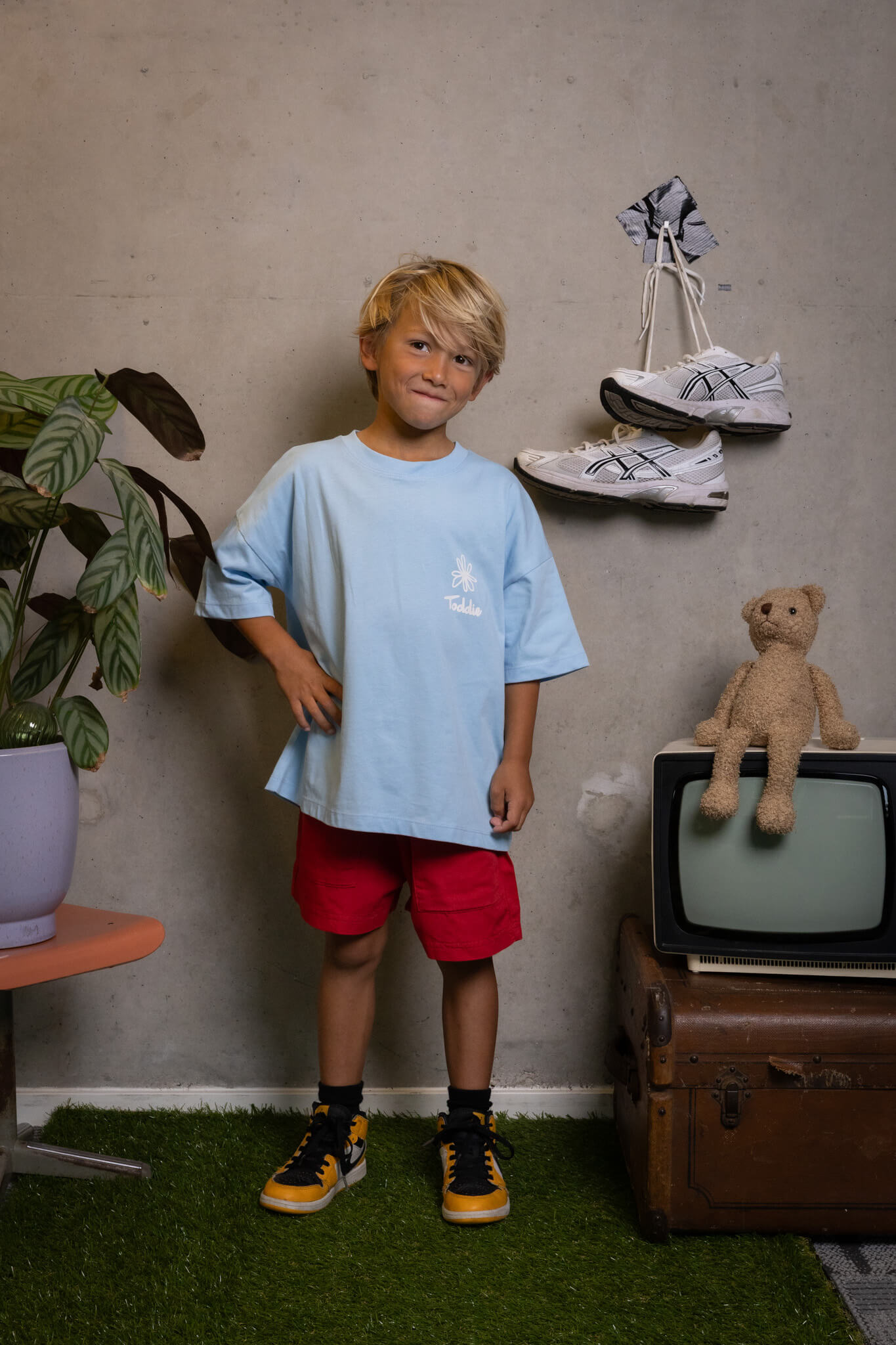 Confident kid rocking Toddie's FIT #5 tee like a boss, red shorts, and yellow kicks ready to conquer—Toddie style.