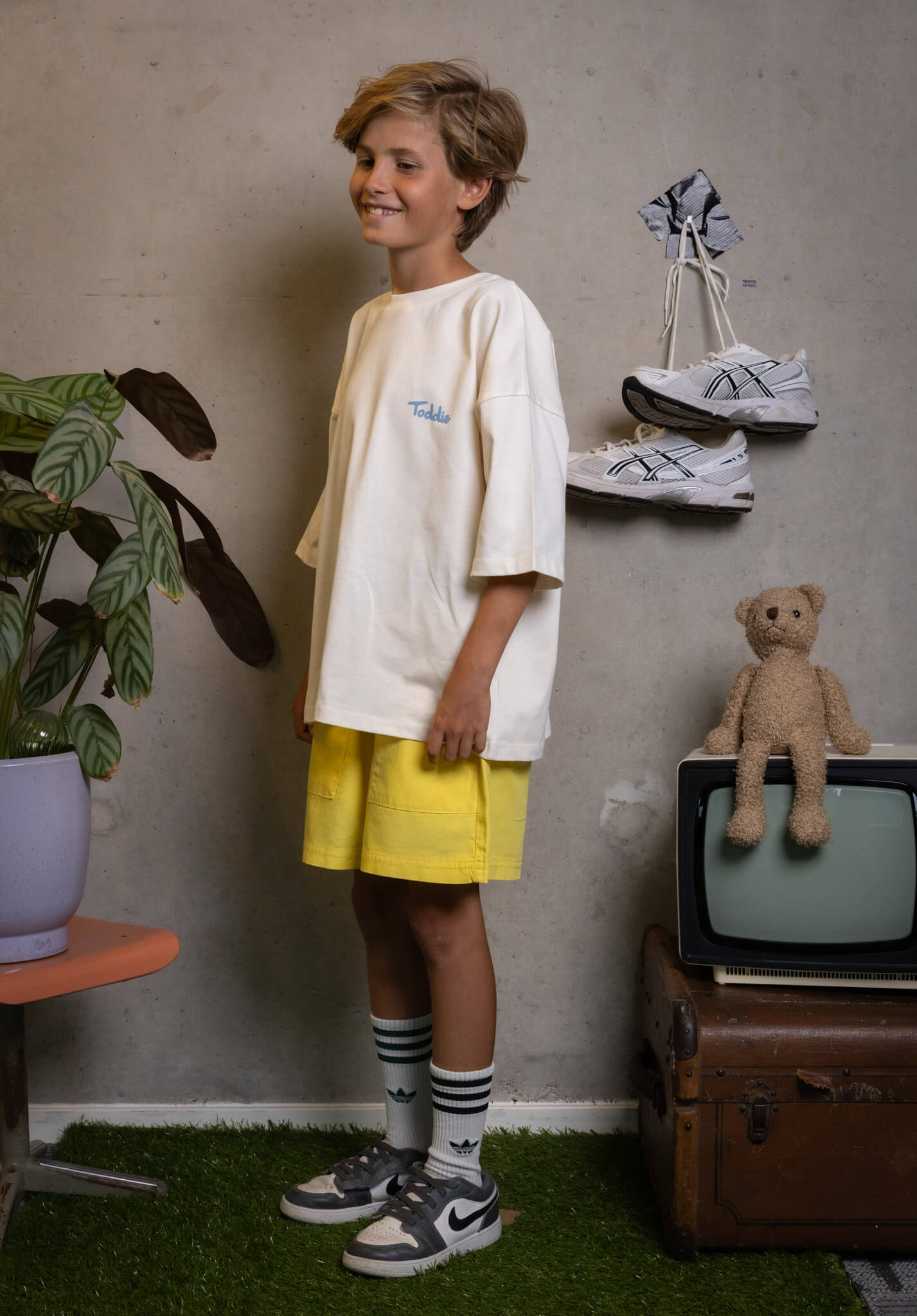 Confident kid rocking FIT #3 tee and yellow shorts, proving style’s real and fun with Toddie.