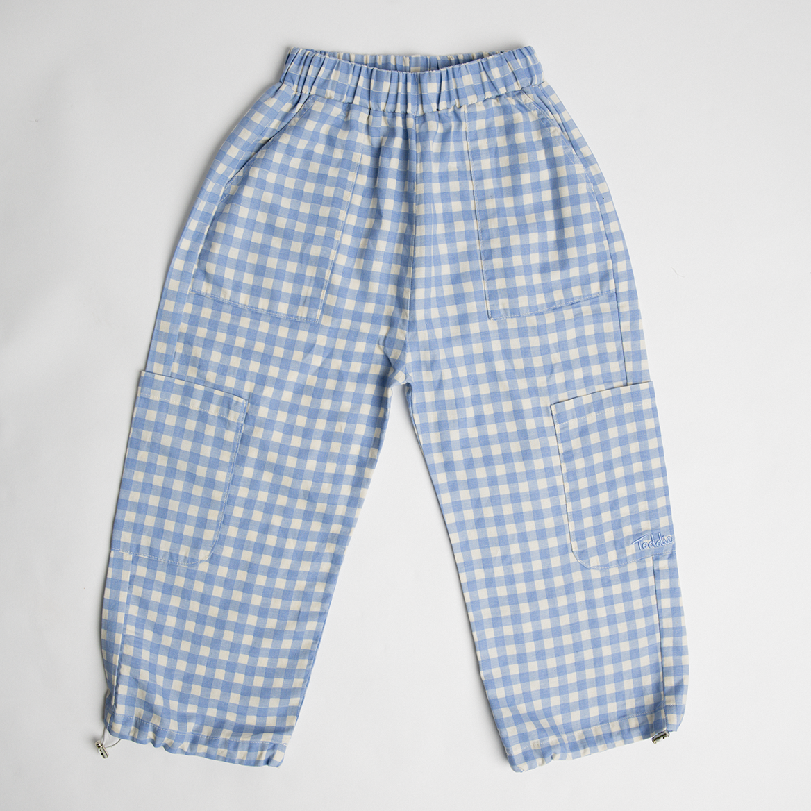 Cargo Gingham Pants in soft blue cotton with baggy fit, side pockets, adjustable hems, and unisex gingham print design.