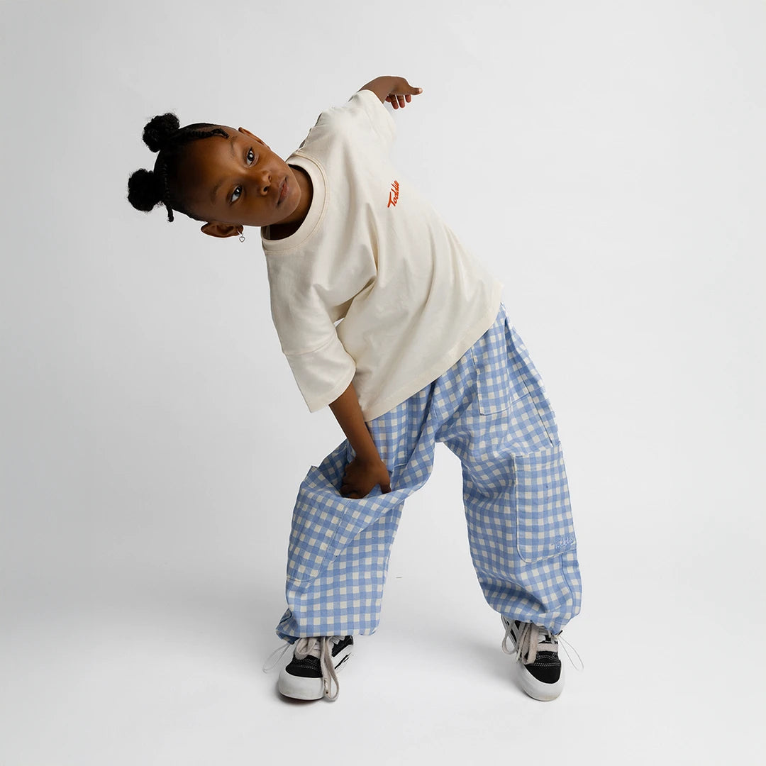 Child wearing relaxed fit blue gingham Cargo Gingham Pants with adjustable hems and side pockets on white background.
