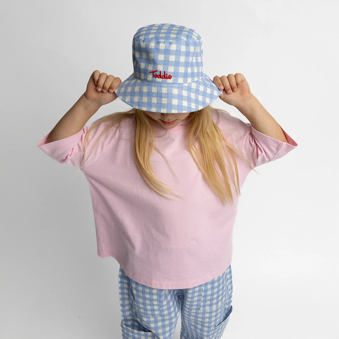 Child wearing a pink Oversized Tee with a blue checkered hat and pants, showing a casual, comfortable look.