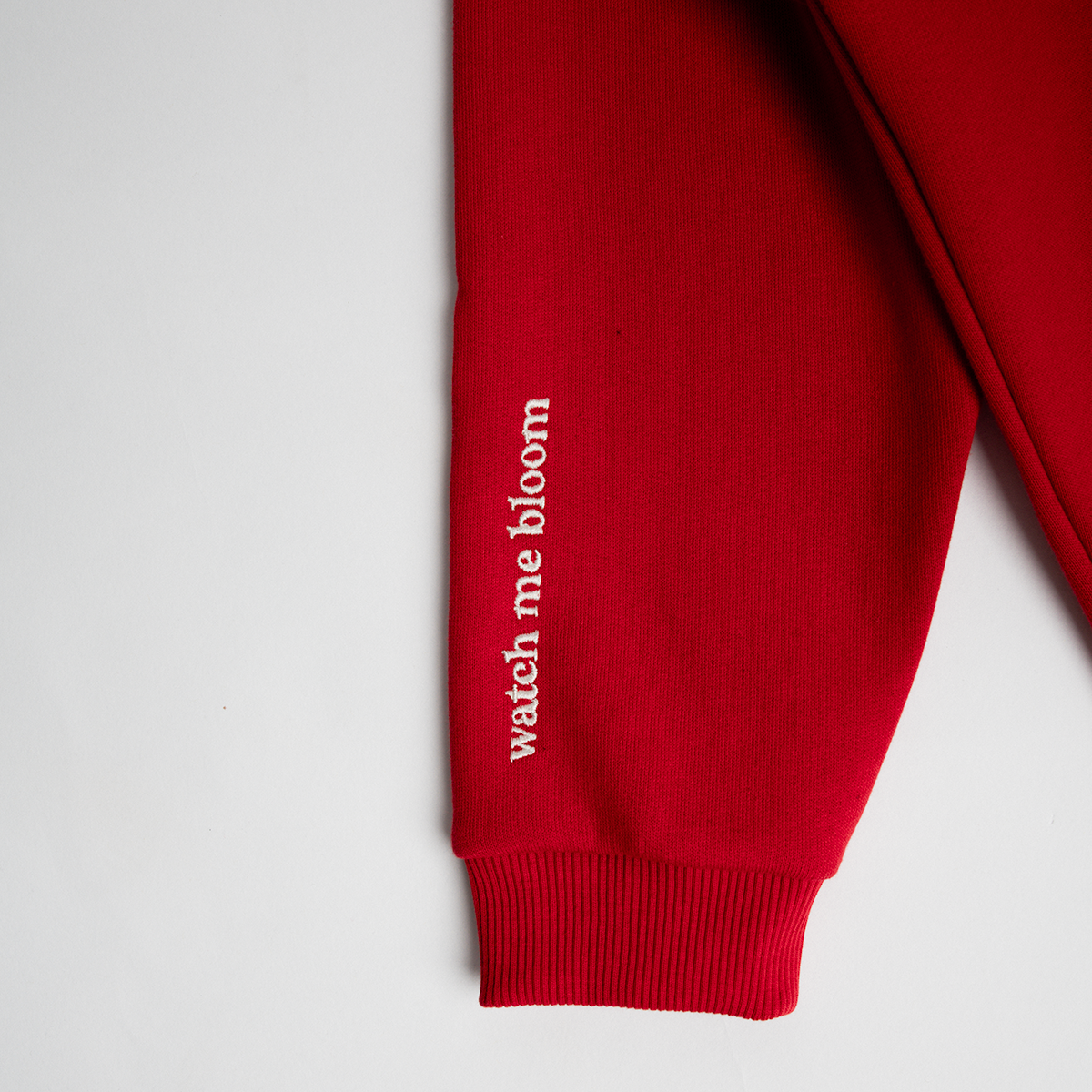 WMB - Oversized Hoodie Red sleeve detail with "watch me bloom" slogan in white embroidery on premium cotton fabric.